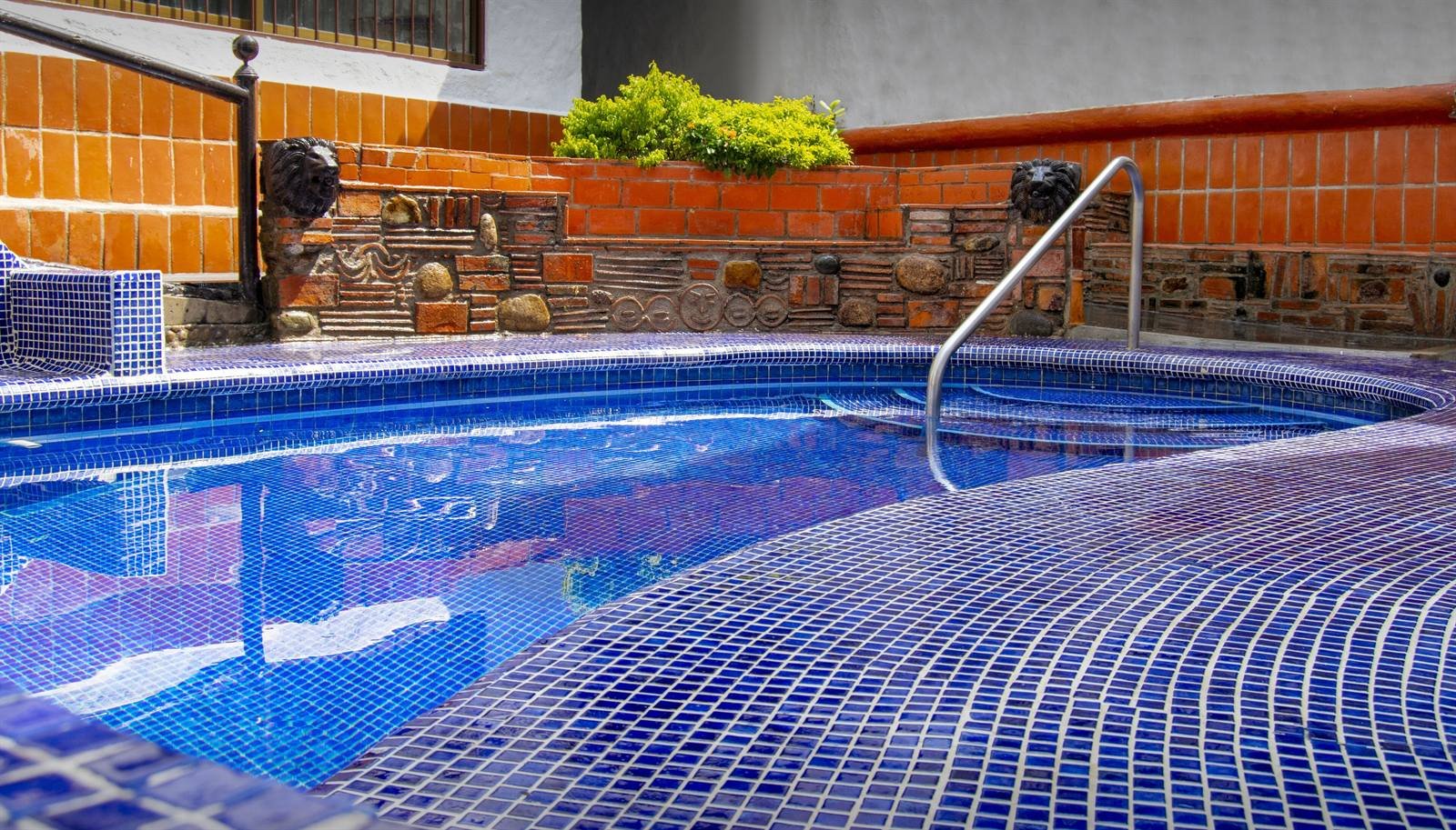 Petit Hotel Pilitas: the pool lined with blue mosaic tiles, with a stone and brick wall