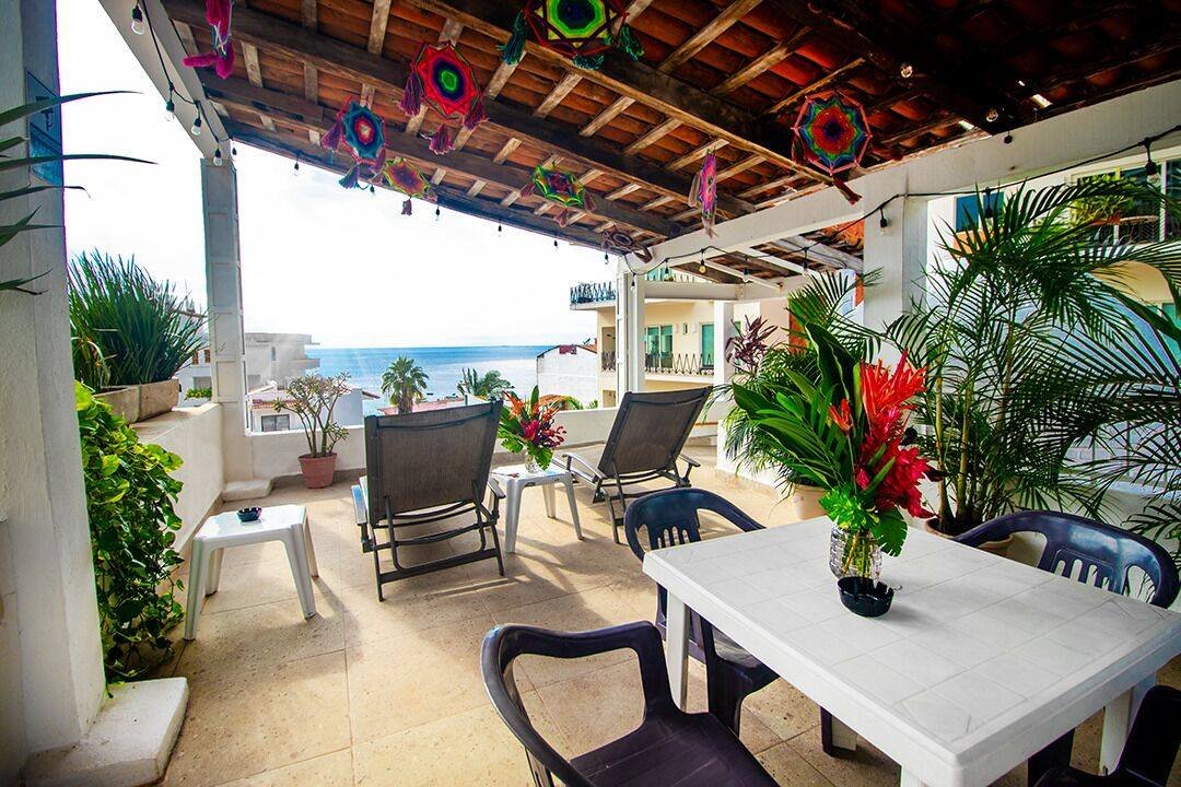 Petit Hotel Pilitas: covered patio with a table, chairs, plants and a glimpse of the ocean